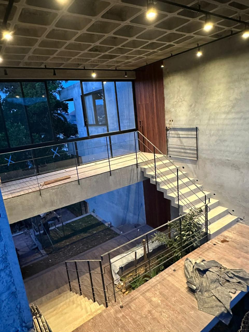 Hall de escada da Casa Olga, com laje nervurada aparente, passarela, guarda-corpo metálico e jardim interno